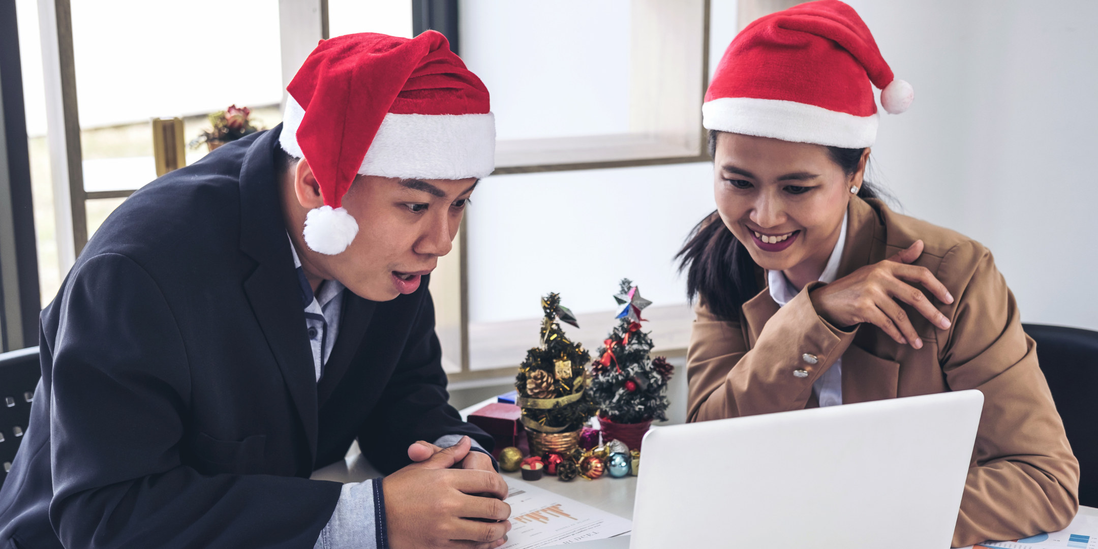 People in santa hats working on a laptop