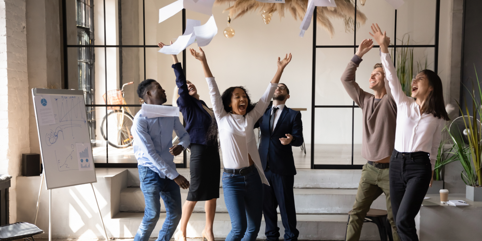 Group of ppl celebrating and throwing paper in the air